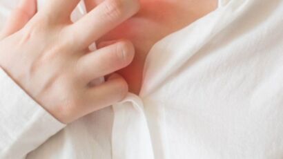 woman in white shirt scratching her chest