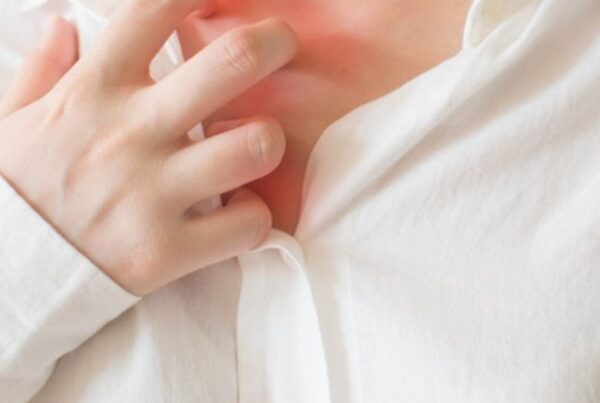 woman in white shirt scratching her chest